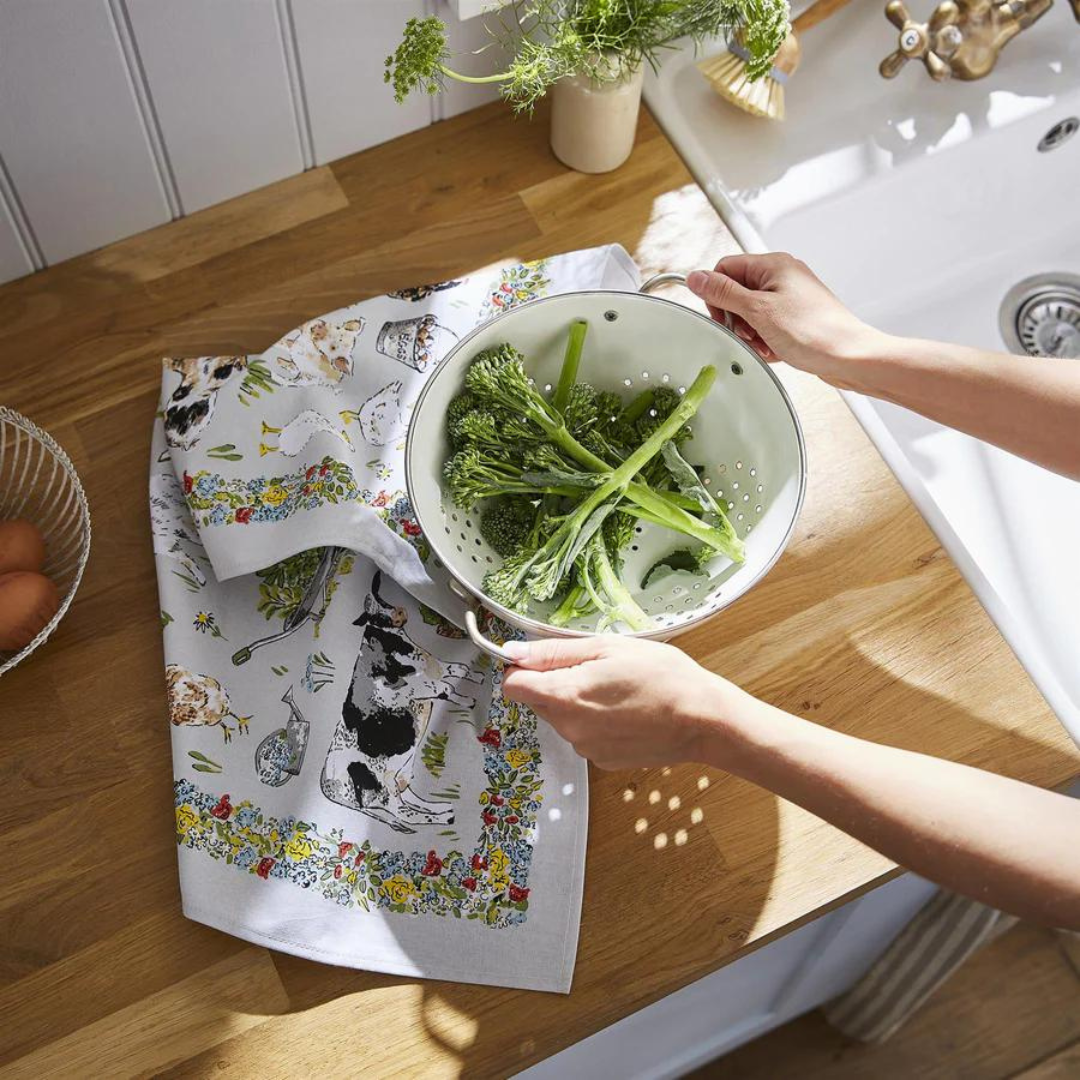 Hands holding colander with fresh broccolini over wooden countertop