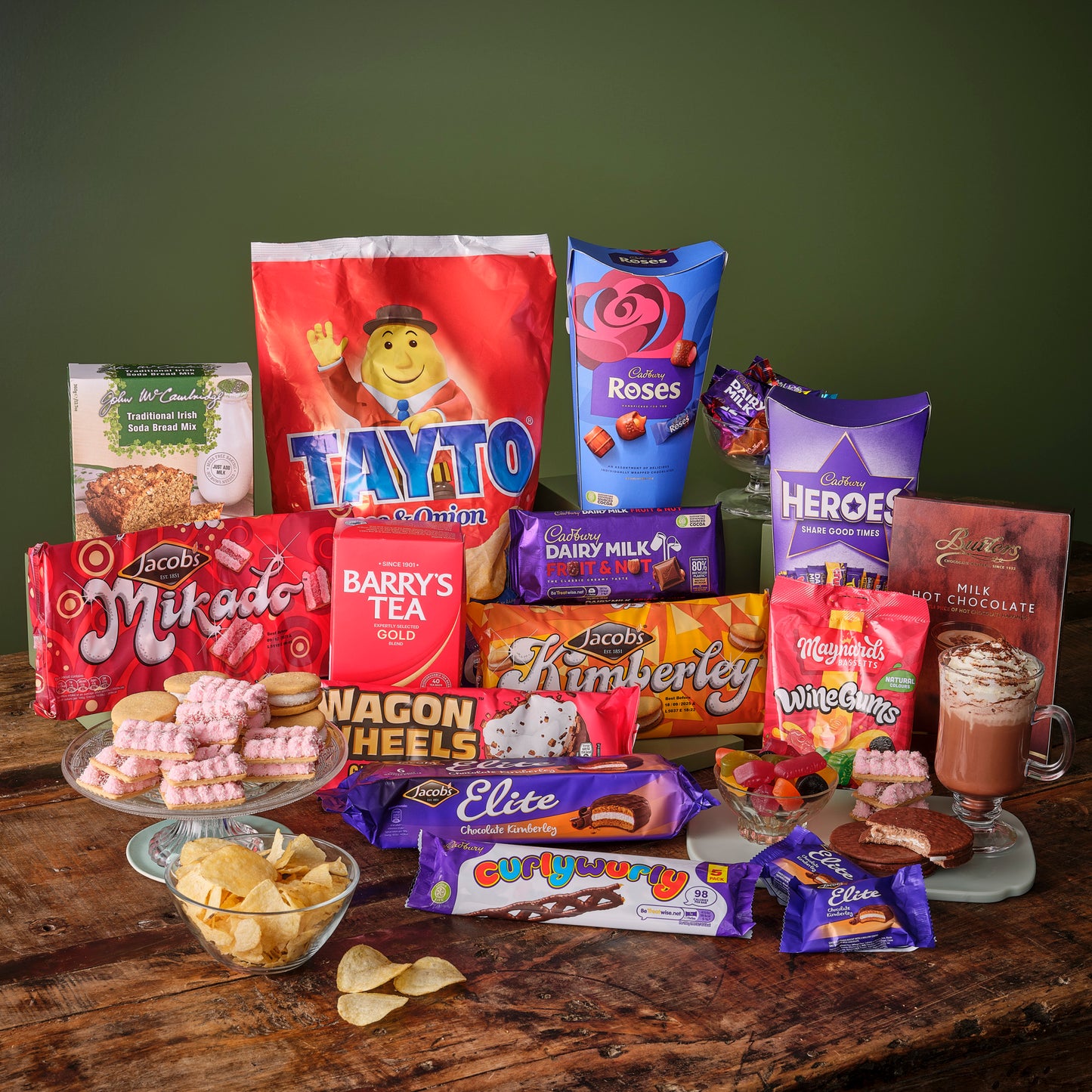 Assortment of snacks, chocolates, biscuits, and sweets on wooden table