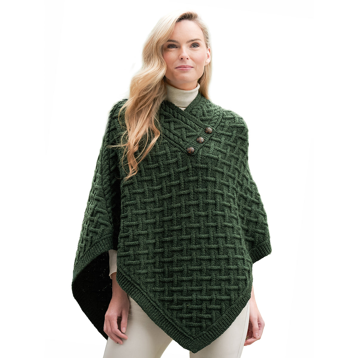 Model wearing a dark green merino poncho with a chunky lattice knit and three buttons at the collar