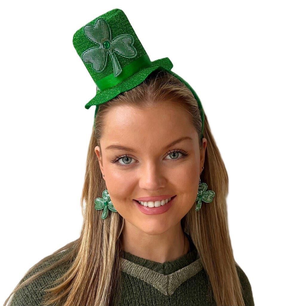 Smiling woman wearing green shamrock earrings and a small green hat headband