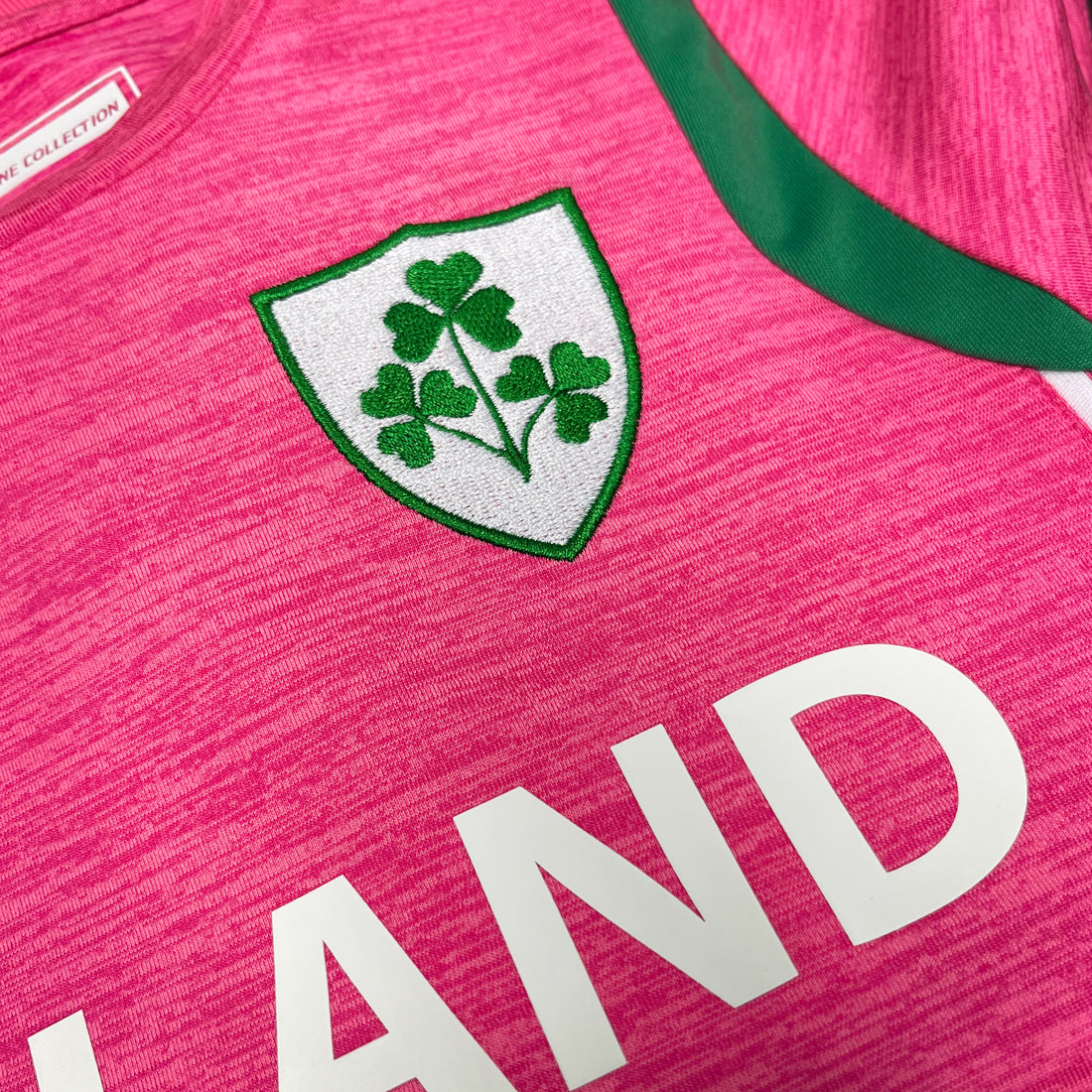 Pink sports jersey with green shamrock emblem and white lettering