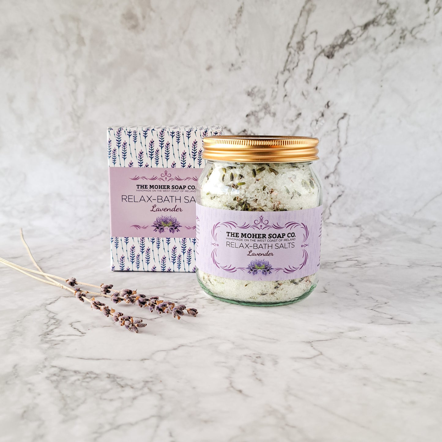 Lavender Relax Bath Salts in a glass jar with copper lid beside a decorative patterned box.