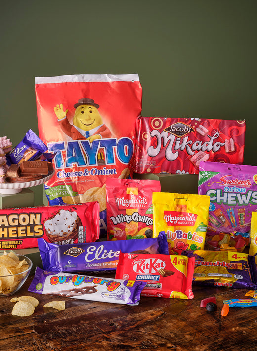 Assortment of colorful packaged snacks and sweets on wooden surface