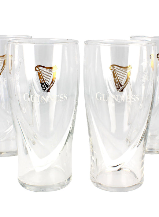 Four clear pint glasses with gold harp logos and Guinness text