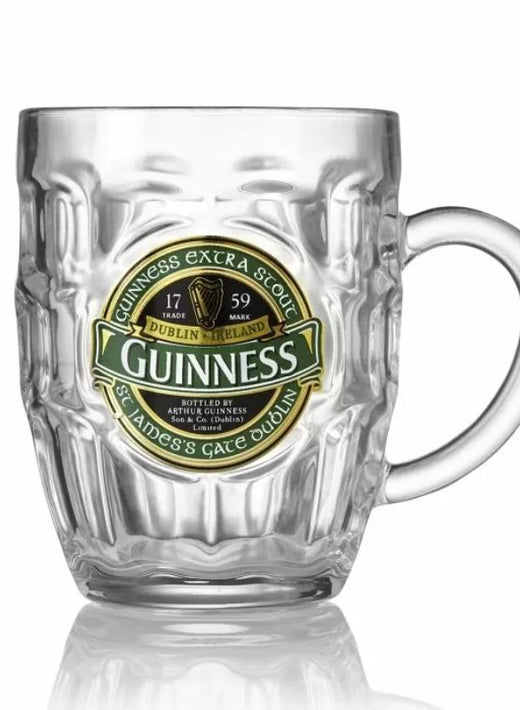 Clear glass beer mug with Guinness logo and handle on white background