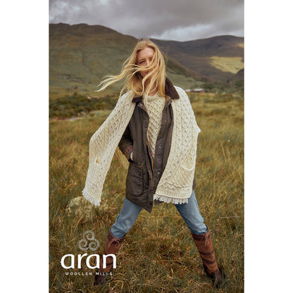 Model wearing cream Shannon Merino Aran wrap over a jacket in a windswept countryside setting.