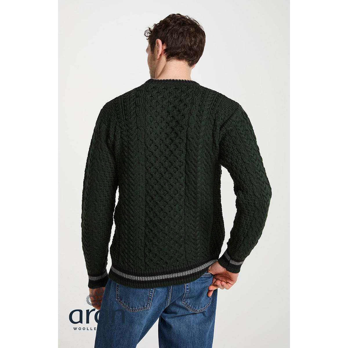 Back view of model wearing dark green Aran cable knit sweater with striped hem.