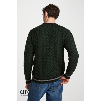 Back view of model wearing dark green Aran cable knit sweater with striped hem.
