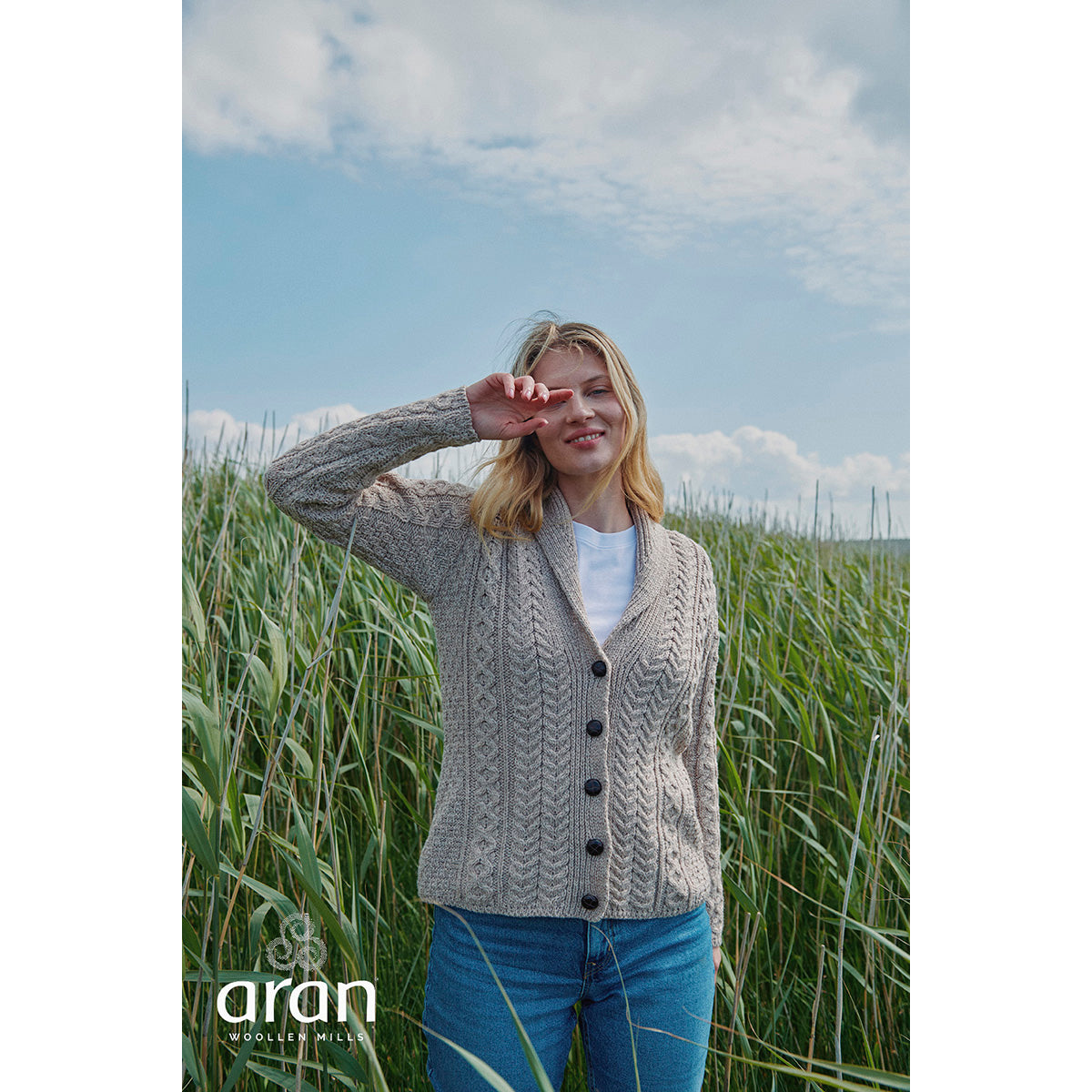 Womens Tourmakeady shawl collar Merino Aran cardigan on a model in a field of tall grasses