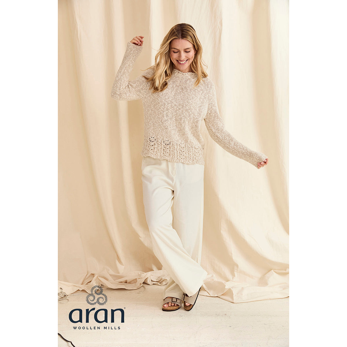 Model wearing cream cotton linen crew sweater with a lace hem against a beige backdrop.