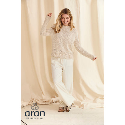 Model wearing cream cotton linen crew sweater with a lace hem against a beige backdrop.