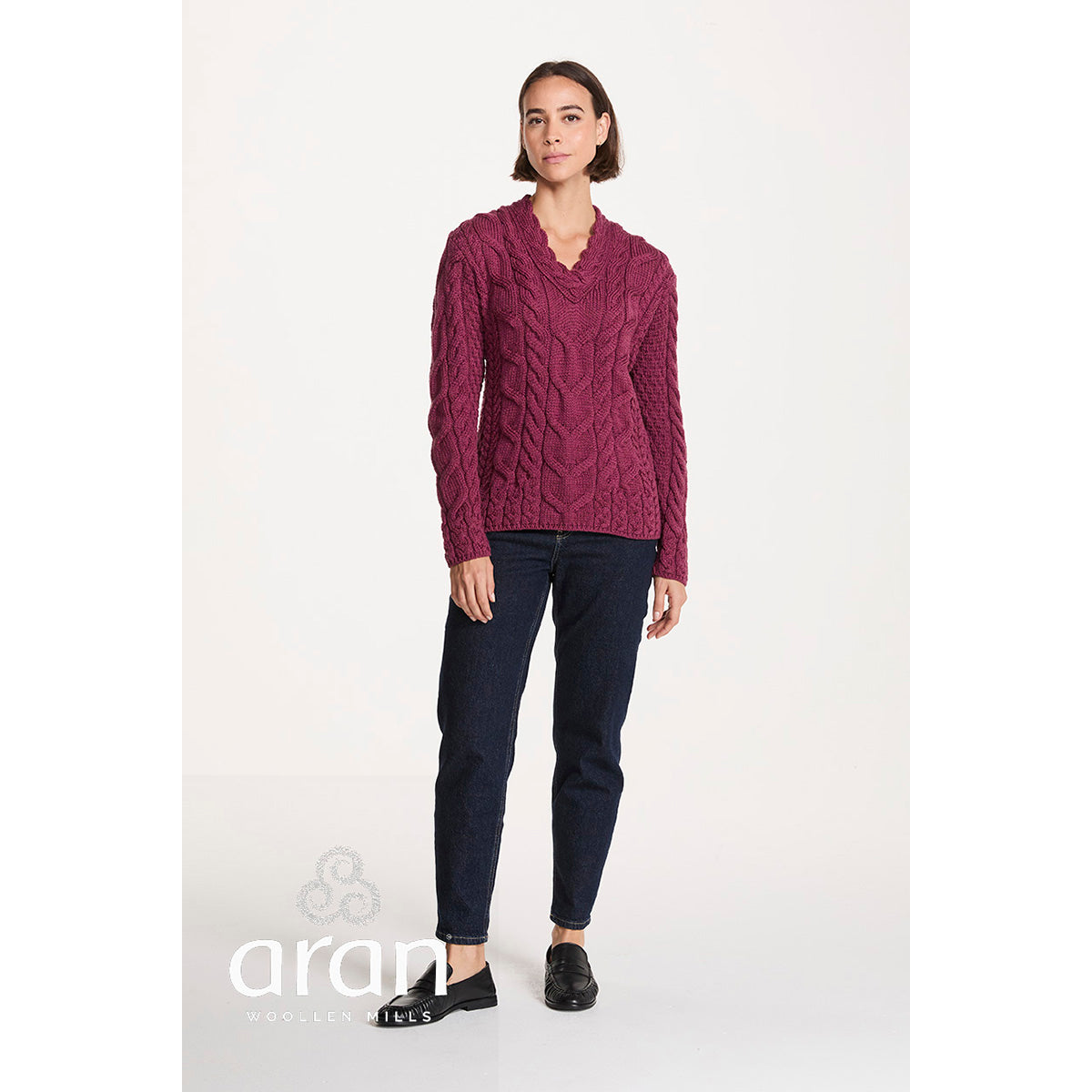 Full body shot of a model wearing a berry Tralee V-Neck Merino sweater with dark jeans and black loafers.