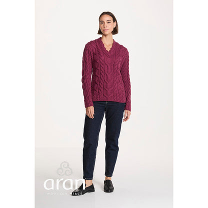Full body shot of a model wearing a berry Tralee V-Neck Merino sweater with dark jeans and black loafers.