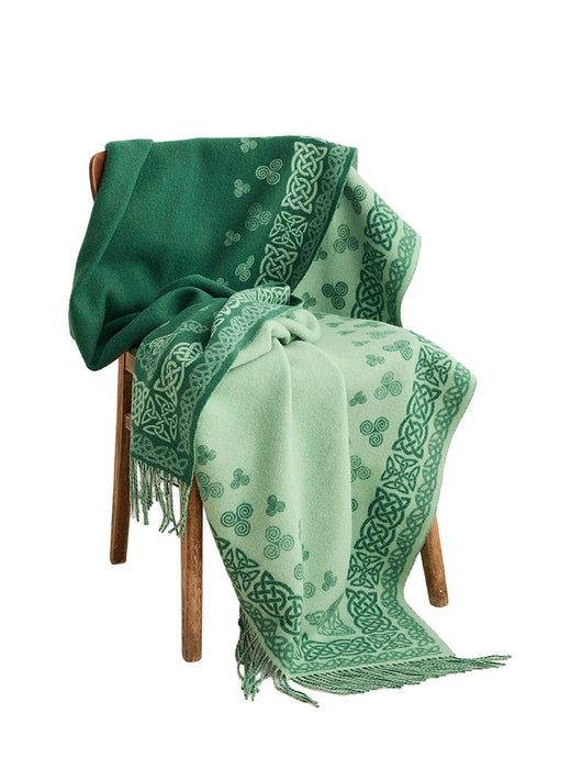 Green Aran blanket with Celtic swirl border draped over a chair.