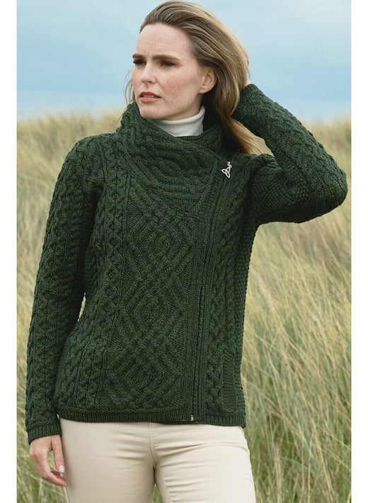 Woman wearing dark green cable knit sweater standing in grassy field