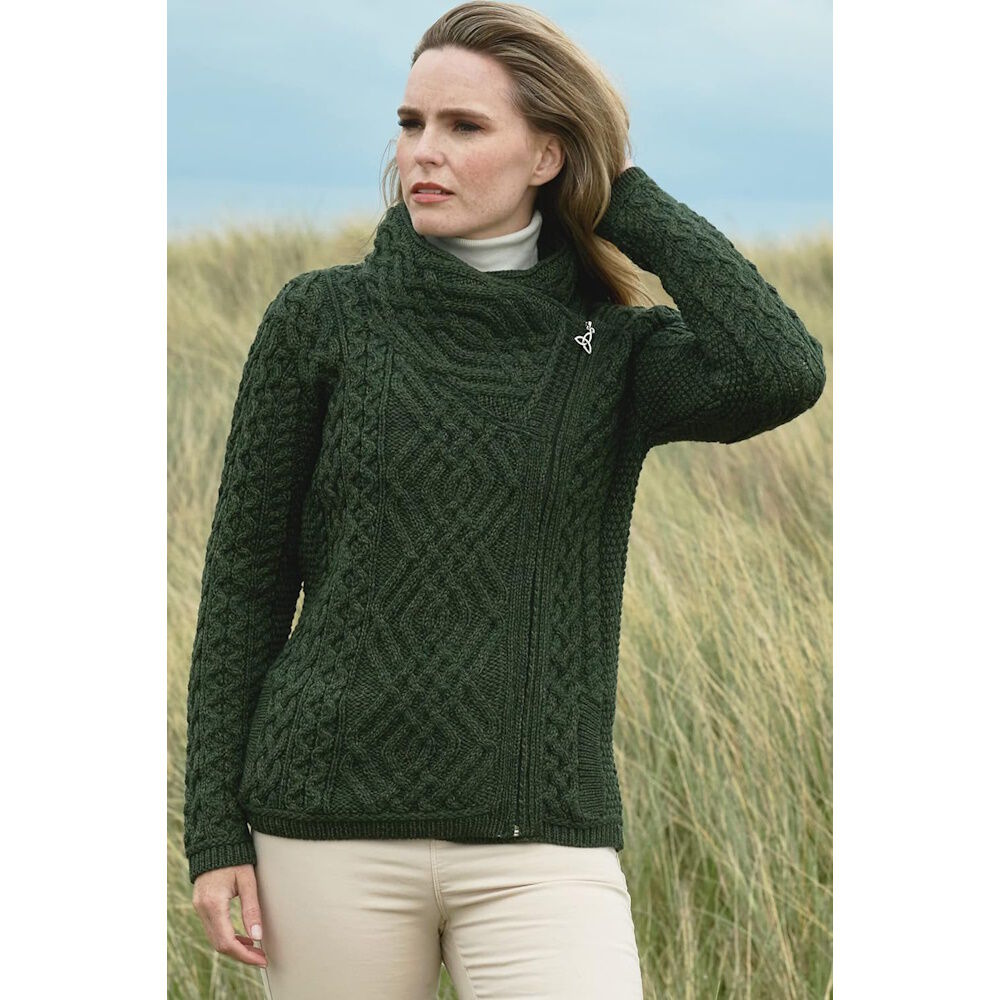 Woman wearing dark green cable knit sweater standing in grassy field