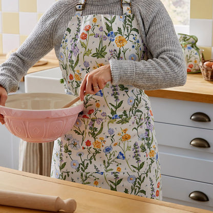 Person wearing a Cottage Garden floral apron while stirring ingredients in a pink mixing bowl