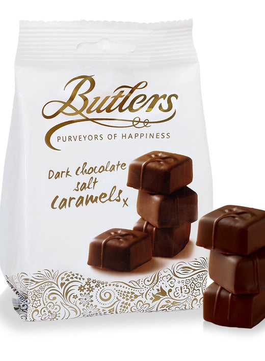 White bag of dark chocolate salted caramels with stacked chocolates beside it