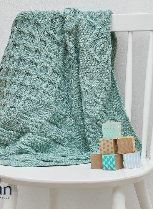 Light blue knitted blanket draped over white chair with wooden blocks