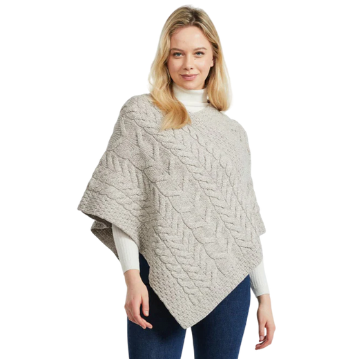 Blonde woman wearing a beige cable knit poncho and white turtleneck
