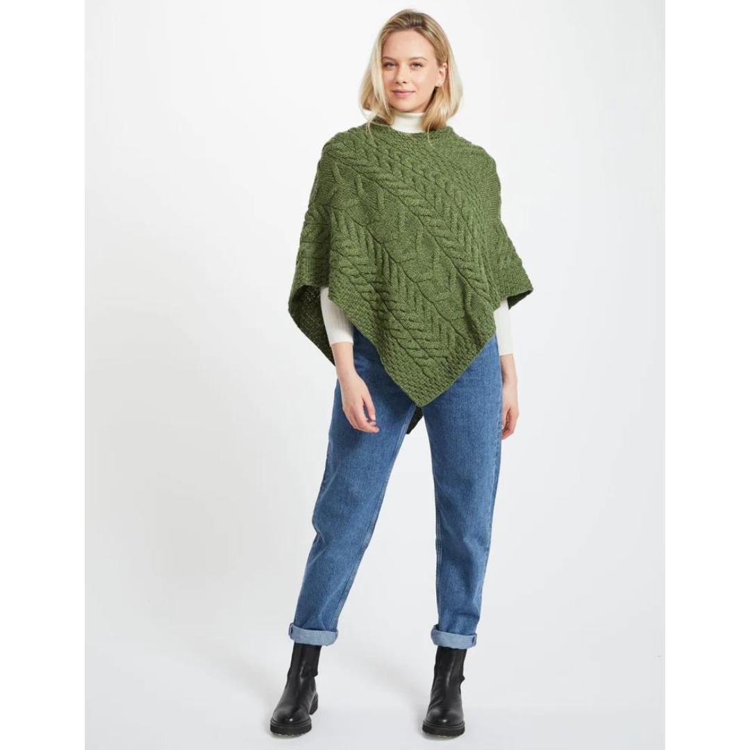 Woman wearing green knitted poncho with blue jeans and black boots