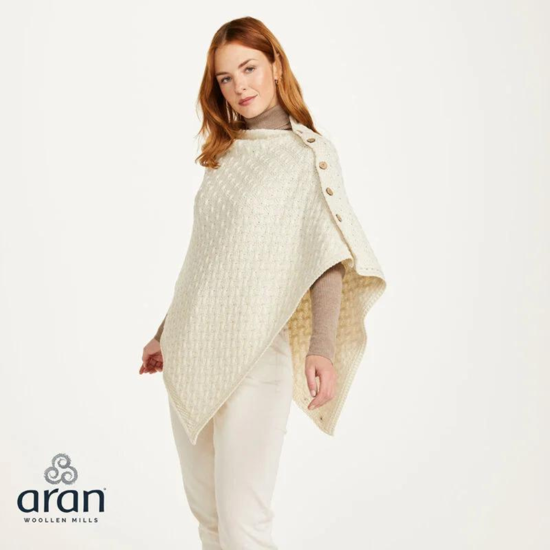 Woman wearing cream knit poncho with buttons over beige turtleneck and pants