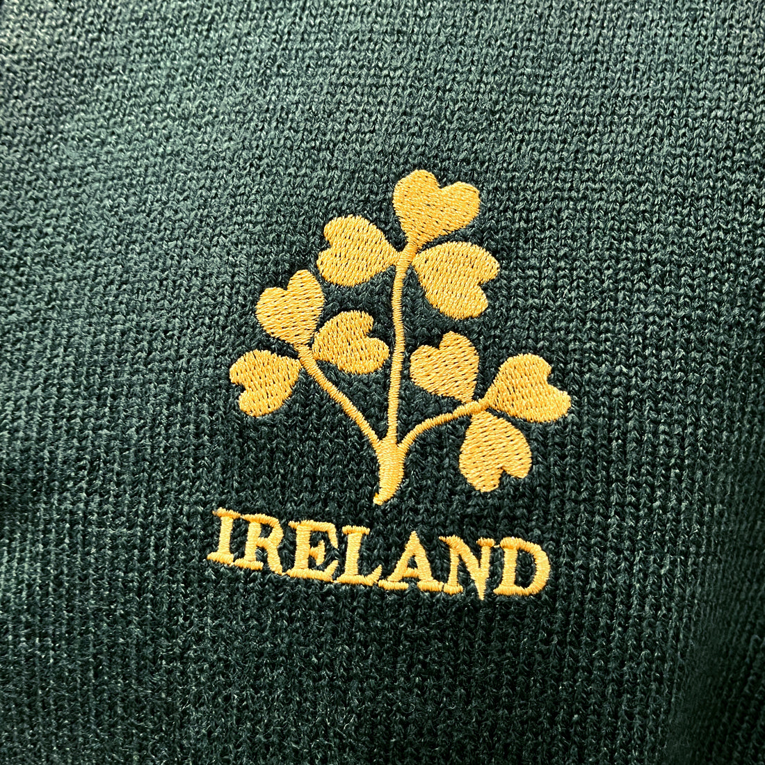 Gold Ireland shamrock embroidery on dark green knit fabric.