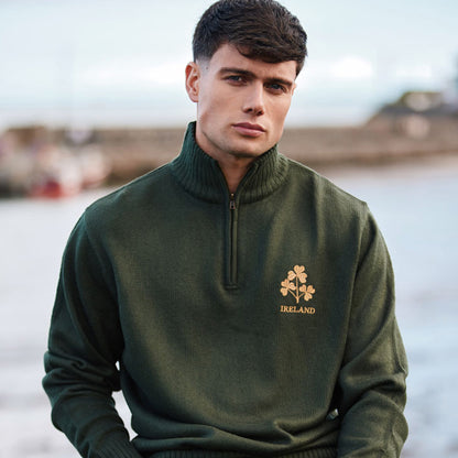 Male model wearing bottle green jumper with gold shamrock embroidery and Ireland text.