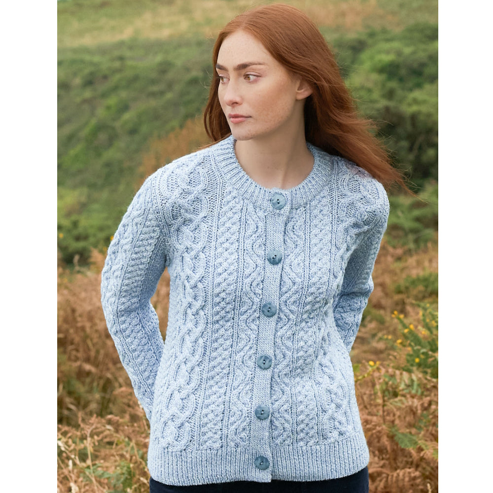Woman with red hair wearing light blue cable knit cardigan outdoors