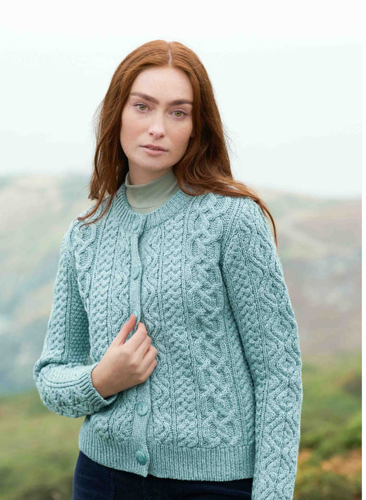 Woman with red hair wearing a light blue knitted cardigan outdoors