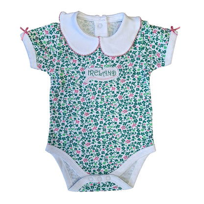 White baby vest with an allover green floral shamrock print and a white collar with pink trim.