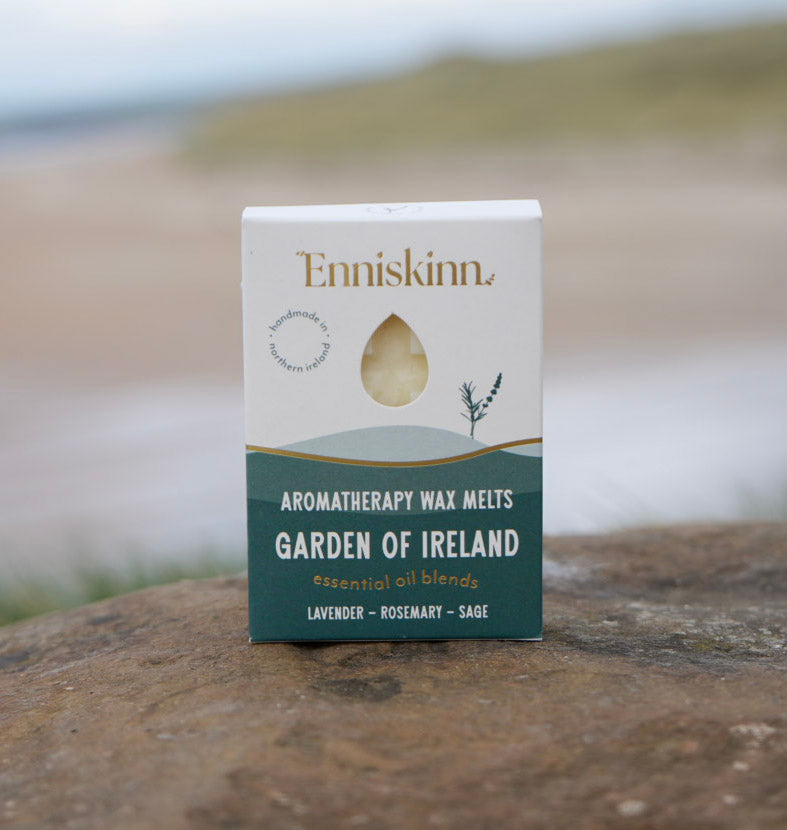 Enniskinn Garden of Ireland Aromatherapy Wax Melts box placed on a rock with a blurred seaside background.