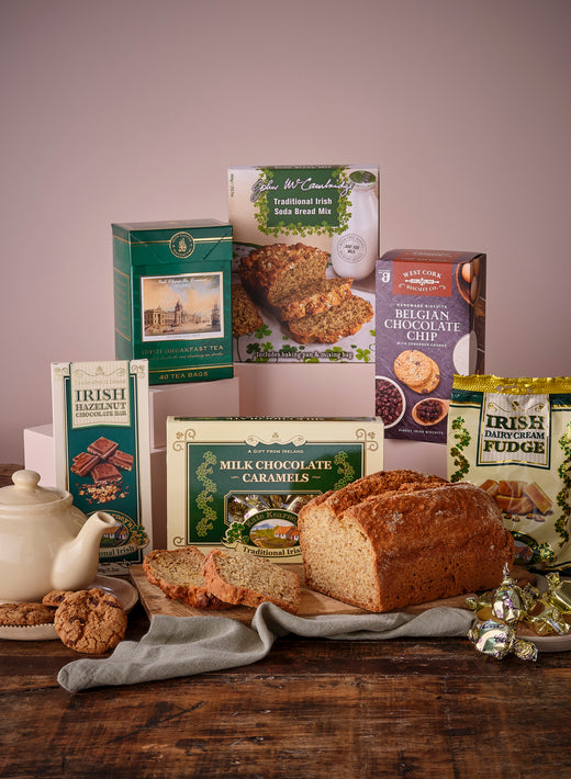 Assorted Irish food items including soda bread, tea, fudge, and chocolates on wooden table