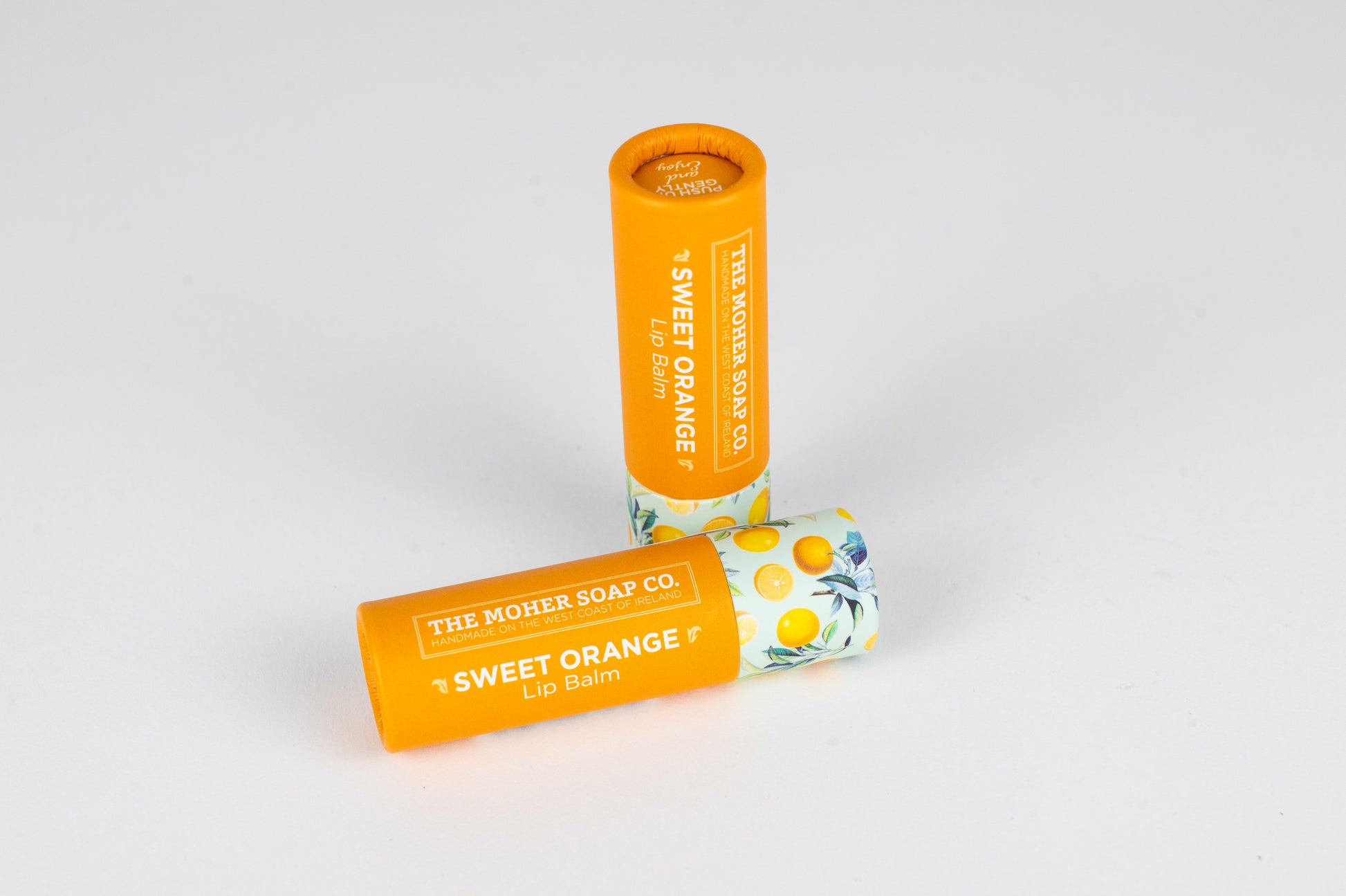 Sweet Orange Lip Balm in a bright orange tube with a citrus themed cap.