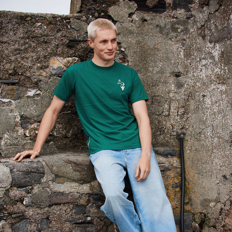 Man in green Guinness Spring Ireland Toucan T-Shirt leaning against a stone wall with back print Ireland Guinness.