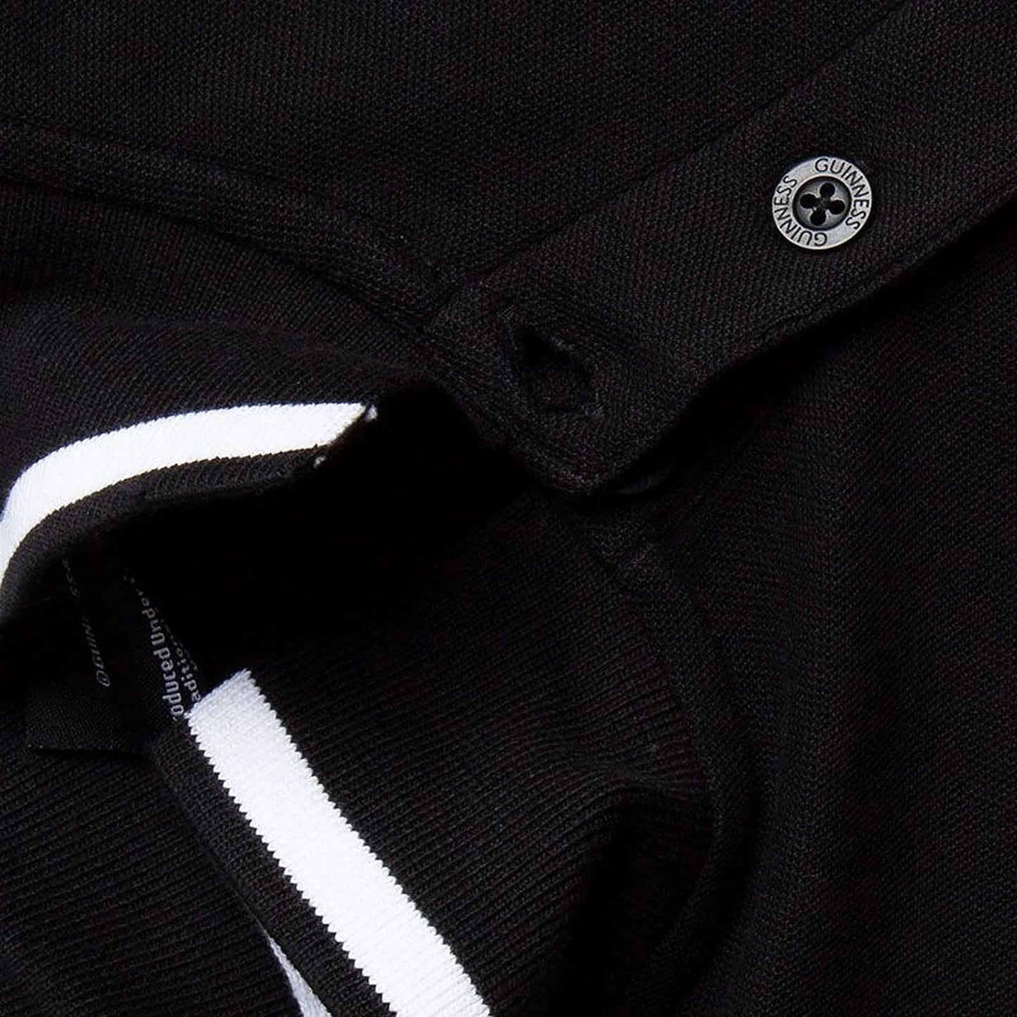 Close up of black polo collar with white stripe and a circular Guinness badge