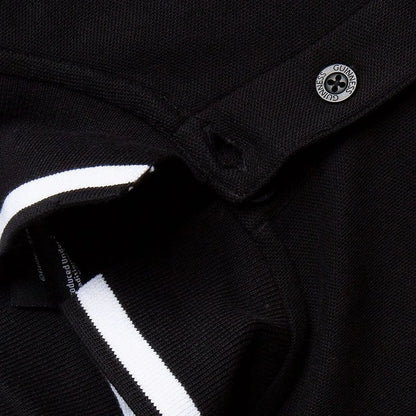 Close up of black polo collar with white stripe and a circular Guinness badge