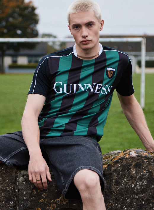 Guinness branded green and black striped soccer jersey worn by a man outdoors