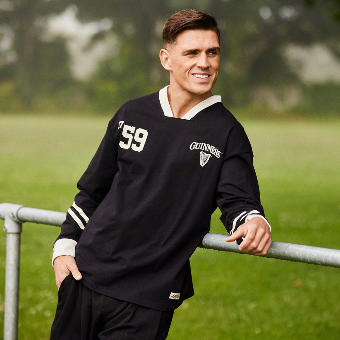 Male model wearing a Guinness black long sleeve American football top with the number 59 and crest outdoors