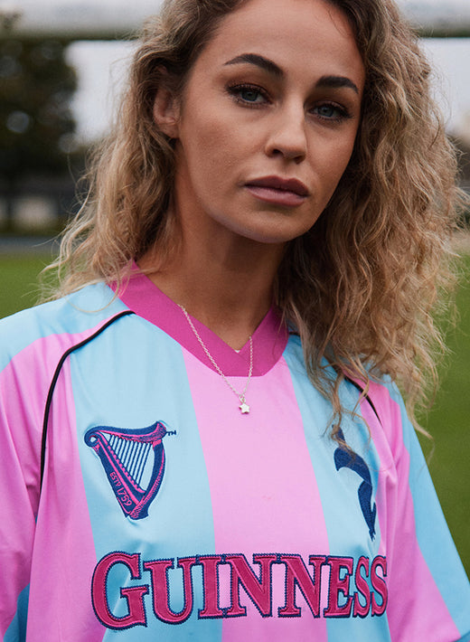 Woman wearing Guinness pink and blue striped performance top outdoors.