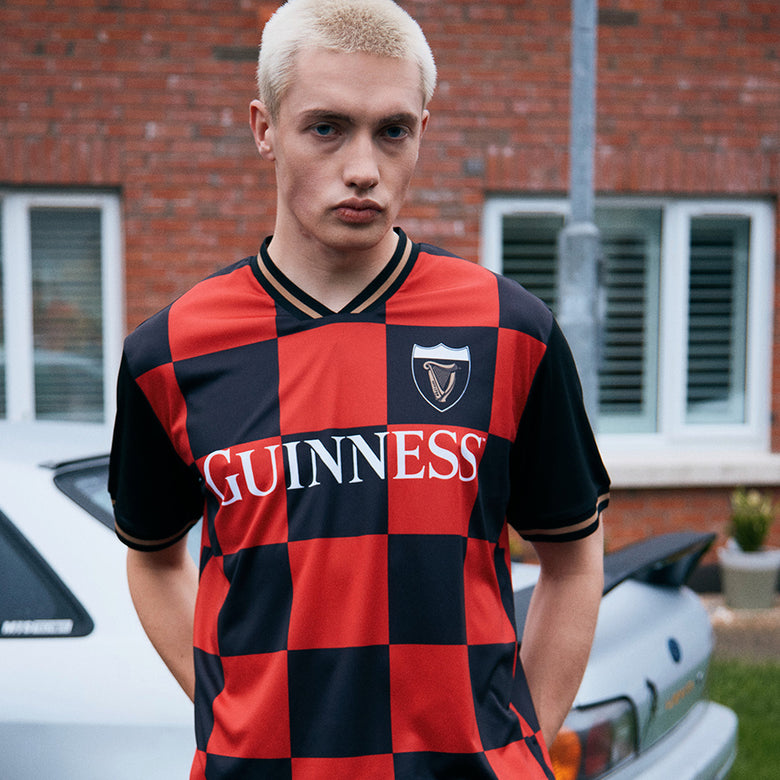 Male model wearing Guinness Black and Red Check Performance Top with crest logo