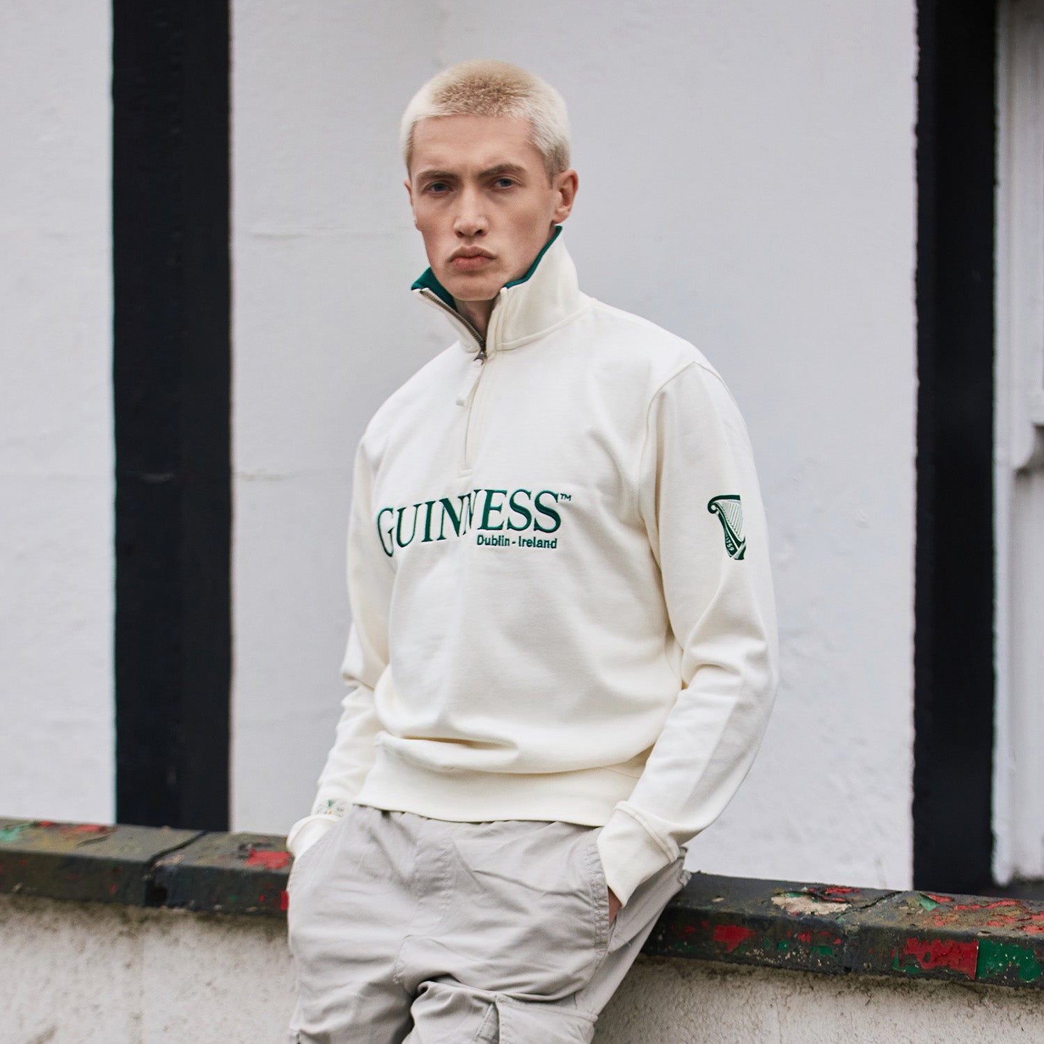 Cream Guinness quarter zip fleece with green logo and harp on the sleeve worn by a man.