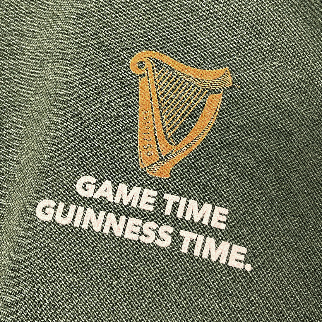 Gold harp emblem with the words GAME TIME GUINNESS TIME on green fabric