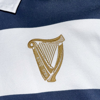 Gold Guinness harp logo embroidered on a white stripe of the navy and white rugby sweatshirt
