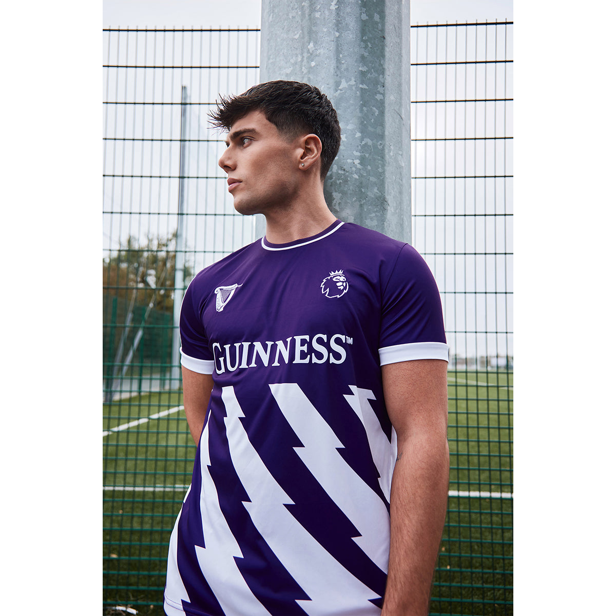 Guinness purple Premier League football top with white chevron pattern and crest worn by a male model