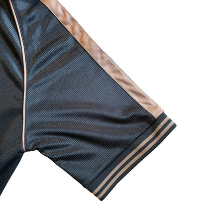 Close-up of dark navy football top fabric with brown piping along the seam and striped cuff.