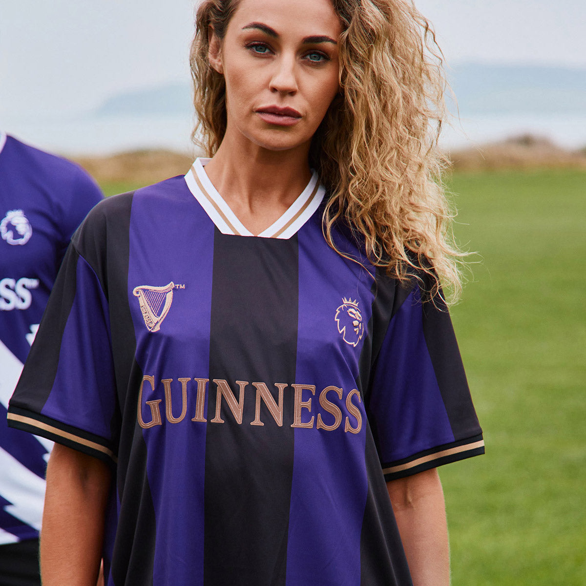 Woman wearing purple and black Guinness football top with crest and gold lettering