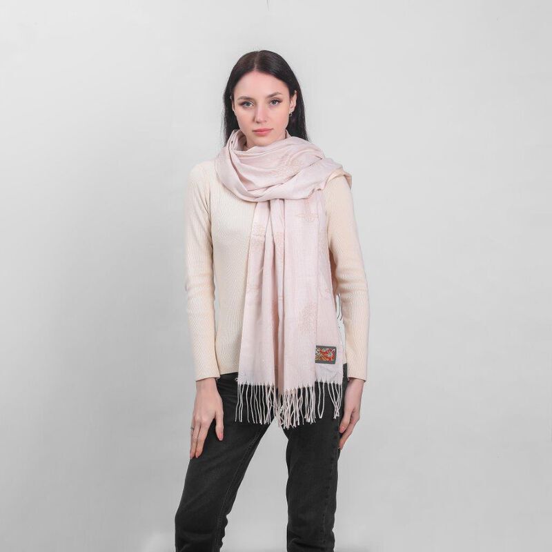 Woman wearing light pink scarf and cream sweater with black pants