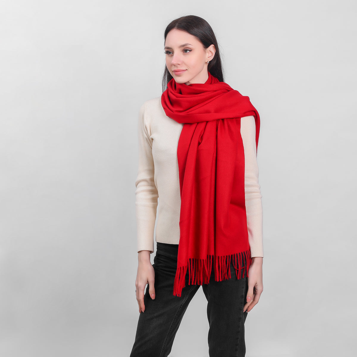 Woman wearing a bright red scarf over a cream sweater and black pants