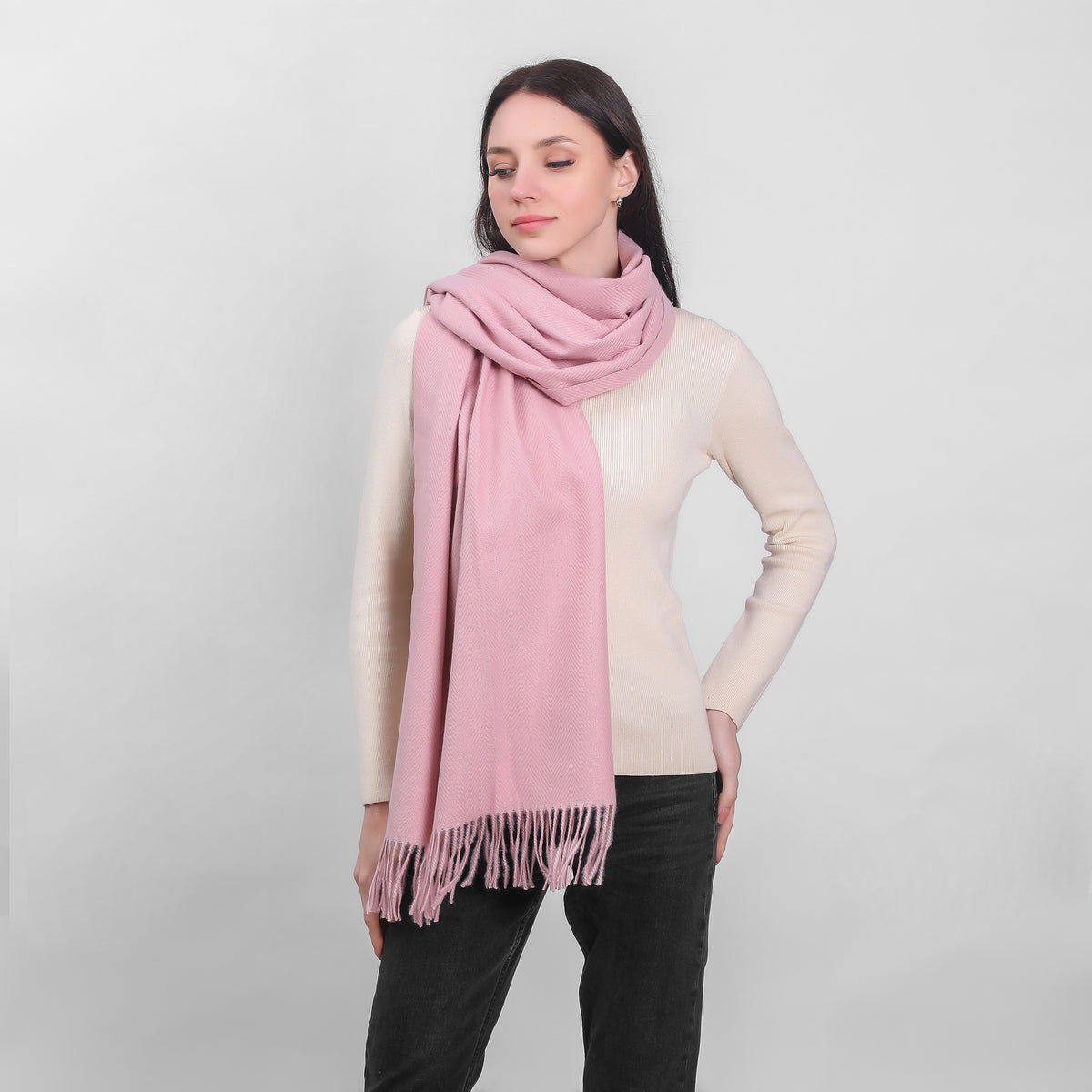 Woman wearing a large pink scarf and cream sweater with black pants
